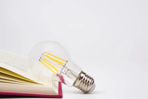 Light bulb glowing with book on white background. Concept of knowledge, wisdom, new ideas and creativity.