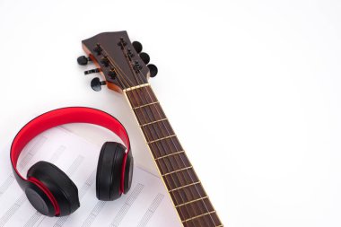 Beyaz arka planda akustik gitar, kulaklık ve müzik notaları. Aşk ve müzik konsepti.