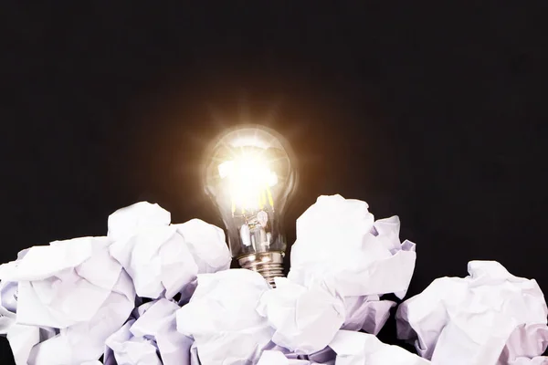 stock image Light bulbs and crumpled paper on black background. Good idea, creativity and inspiration concept.