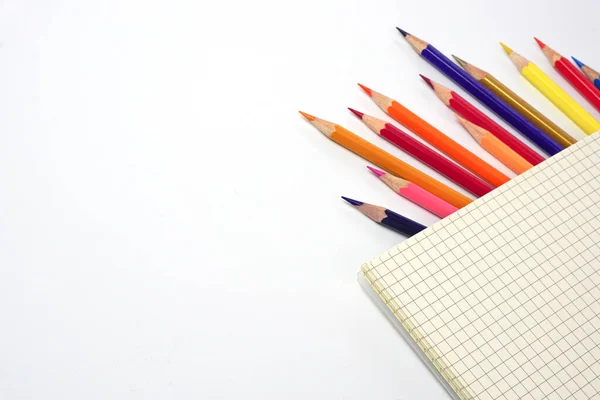 Grafik kitabı ve bulanık renkli kalemler ya da beyaz arka plana dizilmiş pastel kalemler. Öğrenme, öğrenme ve sunum kavramı.