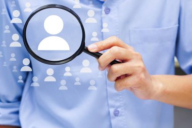 Elinde büyüteç tutan bir iş adamı, organizasyonda personel yönetimi. İnsan kaynakları ve etkili personel kavramı.