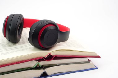 Kulaklıkların odak noktası kitap yığını. Modern eğitim ve rahatlama kavramı.
