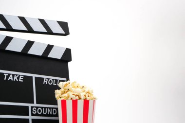 Alkış tahtası ya da film kaplaması beyaz arka planda patlamış mısırlı siyah renkli. Sinema endüstrisi, video üretimi ve film konsepti.