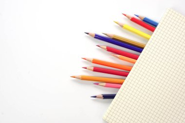 Beyaz zemin üzerinde renkli kalemler ya da pastel çizgiler olan grafik kitabı. Öğrenme, öğrenme ve sunum kavramı.