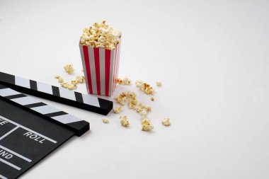 Alkış tahtası ya da film kaplaması beyaz arka planda patlamış mısırlı siyah renkli. Sinema endüstrisi, video üretimi ve film konsepti.