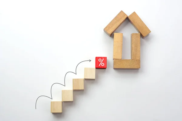 House shape made by wooden block, wooden block stacking as step stair with arrow rising and icon percentage on white background. Interest rate finance, real estate and house loan concept.