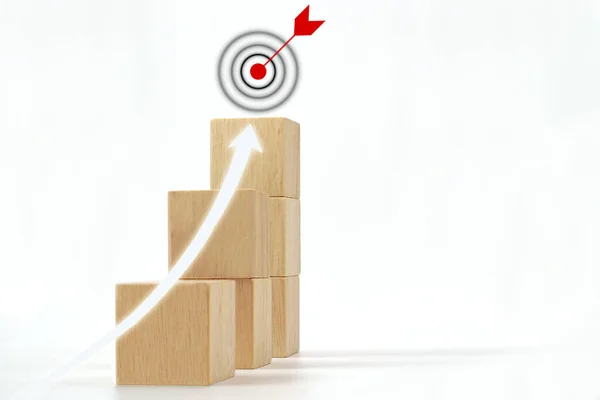 Shining rise up arrow shoot up towards the goal icon on the top of wooden cube block. Concept of business growth, business success goals and strategy planning to success.