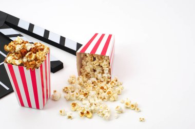 Alkış tahtası ya da film kaplaması beyaz arka planda patlamış mısırlı siyah renkli. Sinema endüstrisi, video üretimi ve film konsepti.