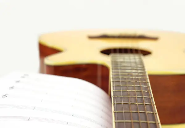 Beyaz arka planda notaları olan akustik gitar. Eğlence, aşk ve müzik konsepti.