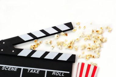 Alkış tahtası ya da film kaplaması beyaz arka planda patlamış mısırlı siyah renkli. Sinema endüstrisi, video üretimi ve film konsepti.