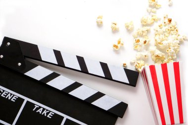 Alkış tahtası ya da film kaplaması beyaz arka planda patlamış mısırlı siyah renkli. Sinema endüstrisi, video üretimi ve film konsepti.