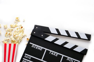 Alkış tahtası ya da film kaplaması beyaz arka planda patlamış mısırlı siyah renkli. Sinema endüstrisi, video üretimi ve film konsepti.