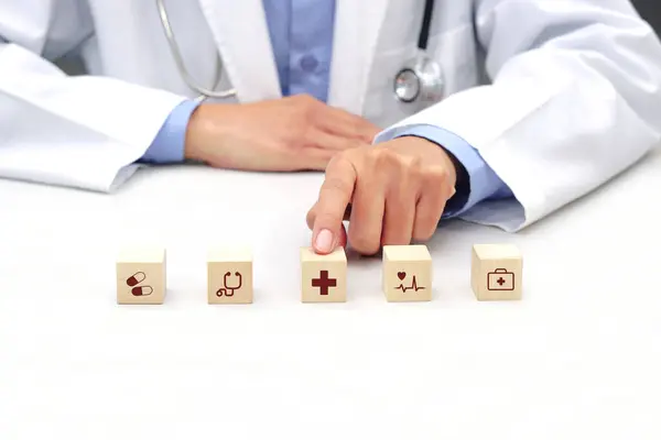 Doktorun parmağı, tıbbi ikon sembolü olan tahta bir küp 'e dokunuyor. Tıbbi, sağlık ve sigorta kavramı.