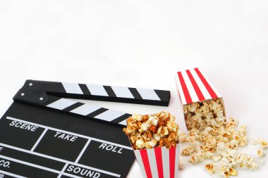 Alkış tahtası ya da film kaplaması beyaz arka planda patlamış mısırlı siyah renkli. Sinema endüstrisi, video üretimi ve film konsepti.