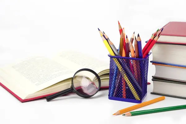 Boya kalemlerini ya da renkli kalemleri kutuya ve büyüteçlere odakla, beyaz arka planda sıralanmış bulanık kitapları. Öğrenme, öğrenme ve sunum kavramı.