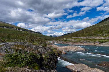 İsveç Kungsleden yürüyüş yolunda kayalarla çevrili vahşi dağ nehri.