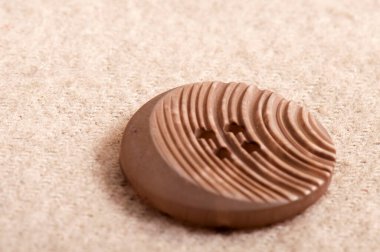 Çizgili kahverengi kumaş üzerinde beyaz plastik bir düğme.