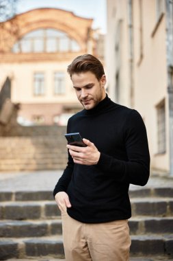 Şık bir adam merdivenlerden inerken akıllı telefonuna odaklanıyor, büyüleyici bir şekilde..