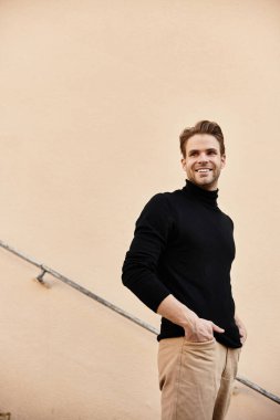 Bir adam kendine güvenen bir gülümsemeyle yürür sıcak bir arka plana karşı, gösterişli bir stil ve cazibe.