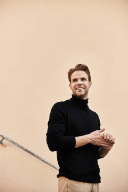 Çekici bir genç adam güneşli bir ortamda yürüyor, gülümsüyor ve anı kucaklıyor..