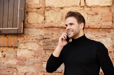 Çekici bir adam güvenli bir şekilde dolaşır, telefonuyla mutlu bir şekilde sohbet eder..