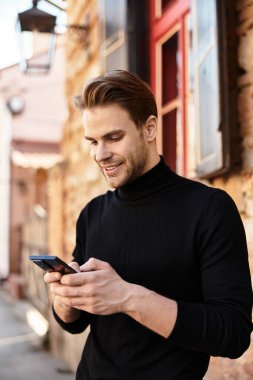 Şık bir genç adam tuhaf bir sokakta yürüyor, akıllı telefonuna dalmış ve gülümsüyor..