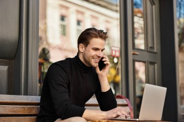 Kendine güvenen ve yakışıklı bir adam telefonda gülümseyerek rahatça dolaşır..