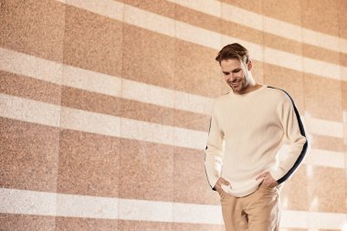 Şık bir adam, modern bir kentsel alanda rahatça dolaşır ve çevresinin tadını çıkarır..