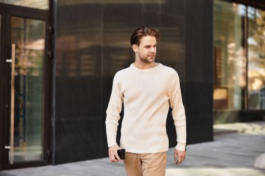 Yakışıklı bir adam güvenli bir şekilde şehir manzarasında dolaşır, gün ışığında güneşlenir..