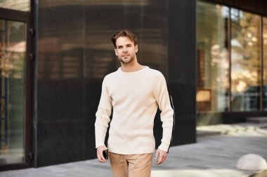 İyi giyimli bir adam, modern bir şehir ortamında sakin bir yürüyüşten, karizmadan ve tarzdan zevk alır..