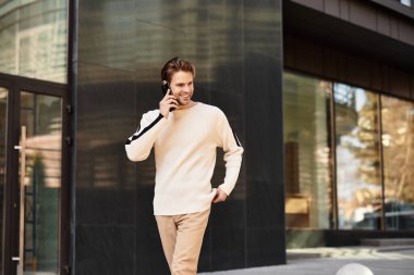 Şık bir adam kaldırımda neşeli adımlarla yürüyor, bir telefon görüşmesi yapıyor..