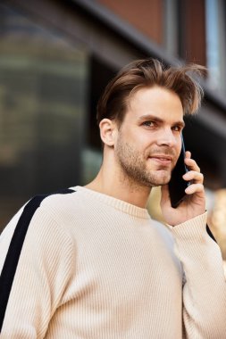Yakışıklı bir adam şehirde yürüyor, cep telefonuyla canlı bir konuşma yapıyor..