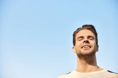 Yakışıklı bir adam gülümseyerek yürür, güneşli bir günün sıcaklığını ve temiz havasını alır..