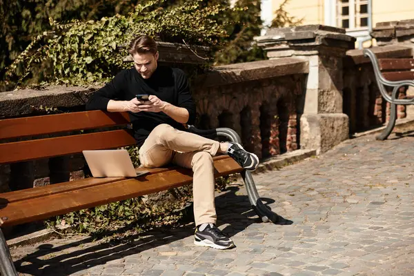 Yakışıklı bir adam, parkta dinlenirken telefonunu kullanarak ara verir..