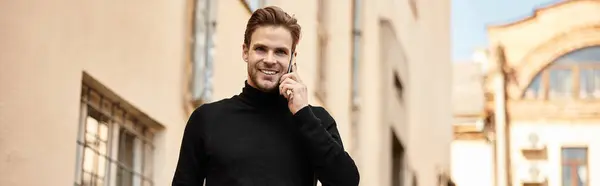 Confident man with stylish hair walks down the street, engaged in a lively phone conversation. — Stock Photo