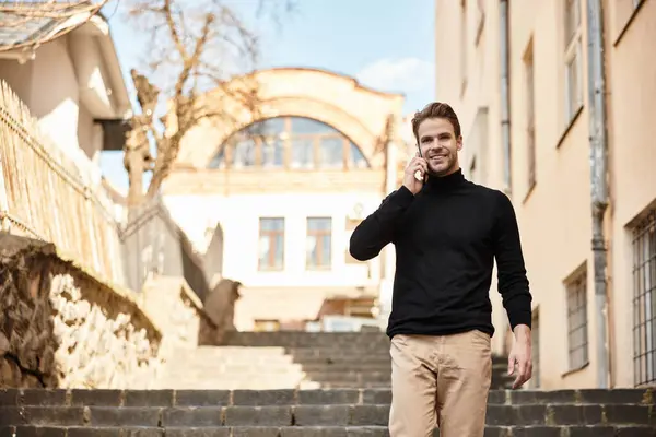 A stylish man enjoys a stroll down beautiful stone steps, chatting animatedly on his phone. — Stock Photo