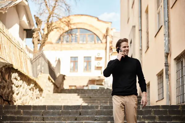 A stylish man walks up the stairs, engaged in conversation on his phone, enjoying the lovely day. — Stock Photo