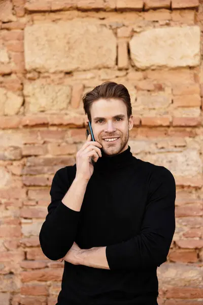 Un uomo sicuro di sé passeggia mentre è impegnato in una vivace conversazione telefonica, sorridendo brillantemente. — Foto stock