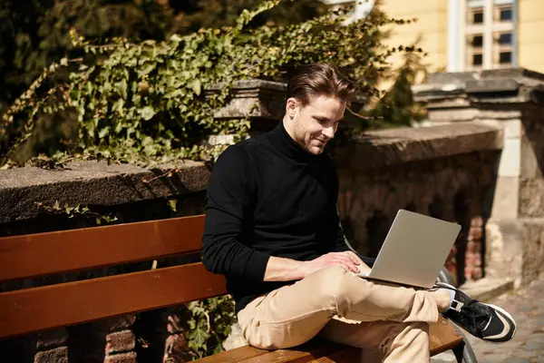 A handsome man walks through a charming area, absorbed in his laptop, mixing work with leisure. — Stock Photo