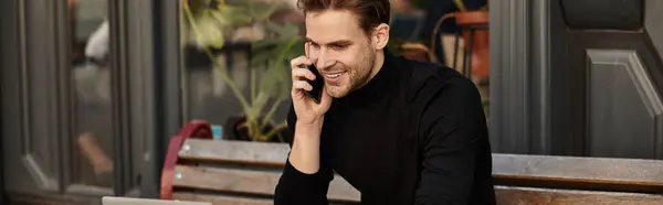 Charming young man walks outside, smiling and conversing on the phone, surrounded by nature. — Stock Photo