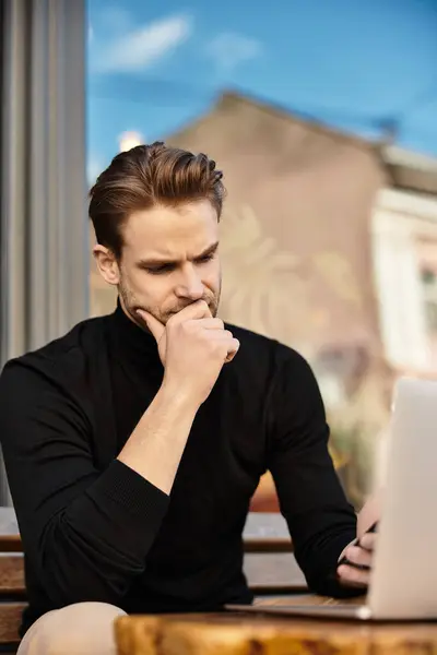 A handsome man sits thoughtfully at an outdoor location, engaged with his laptop. — Stock Photo