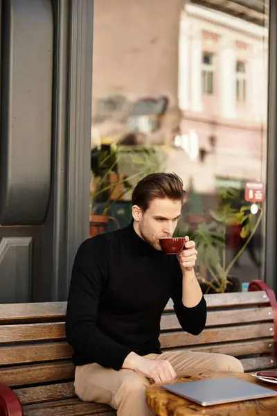 A stylish man takes a moment to sip his drink, surrounded by charming cafe vibes in the city. — Stock Photo