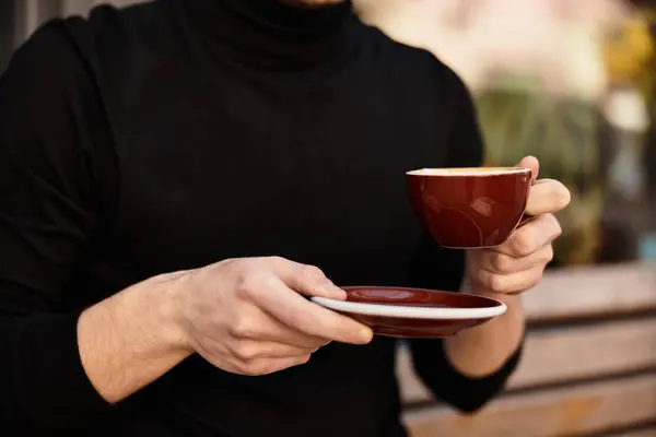 A confident man takes a leisurely stroll outdoors, savoring each sip of his warm beverage. — Stock Photo