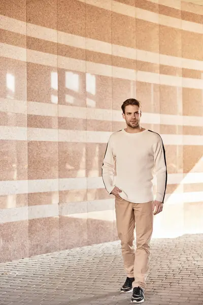 A well dressed man strolls leisurely, showcasing confidence amidst modern design elements. — Stock Photo