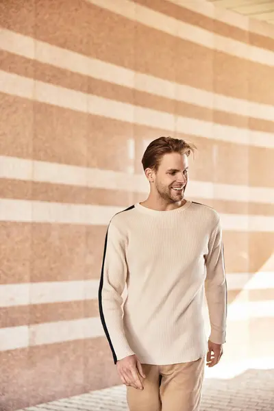 Un uomo allegro passeggia in uno spazio architettonico dalle linee eleganti e dai toni caldi. — Foto stock