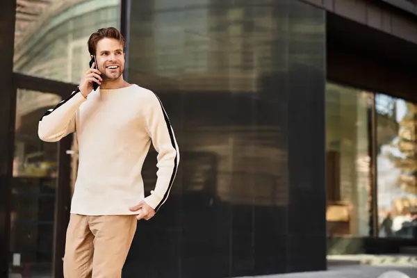 Hell gekleideter Herr geht selbstbewusst und telefoniert in der Nähe eines modernen städtischen Gebäudes. — Stockfoto