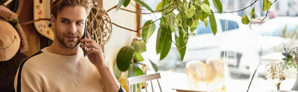 A stylish man engages in a phone conversation, surrounded by warm decor in a cafe. — Stock Photo