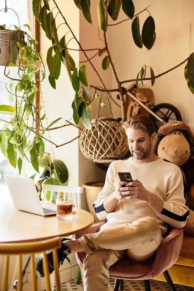 Man in a cozy setting, relaxed as he engages with his smartphone amidst greenery. — Stock Photo
