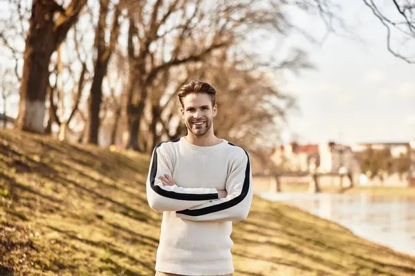 A handsome man walks confidently by the river, surrounded by beautiful trees and natures calm. — Stock Photo