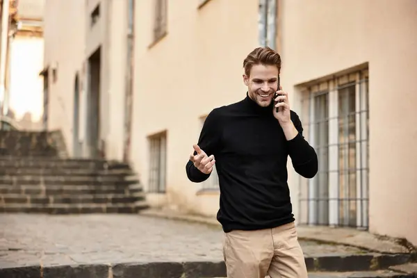 Eine charmante Person schlendert durch eine Straße der Stadt und führt ein fröhliches Telefongespräch. — Stockfoto